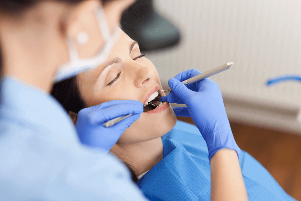 Dentist using dentist hooks to check her patient's mouth canals