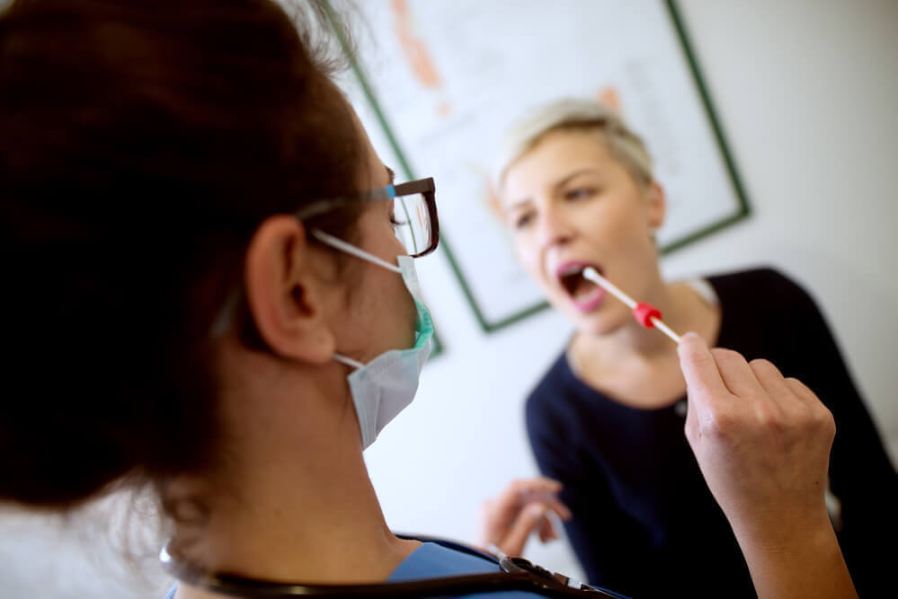 Female dentist putting a swab in her patients mouth