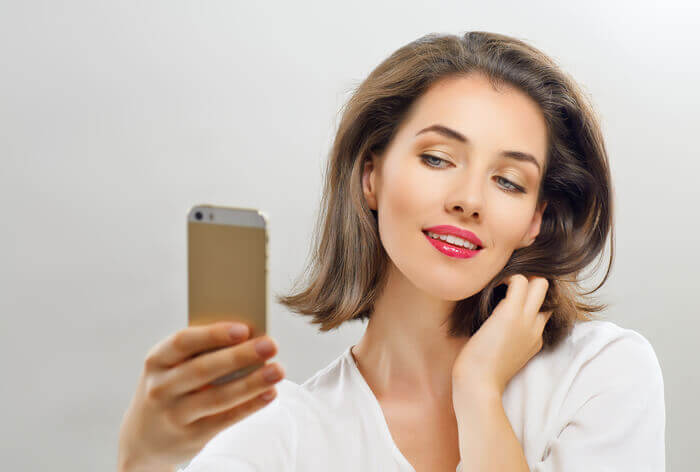 Young woman taking a selfie with a smartphone in her hand