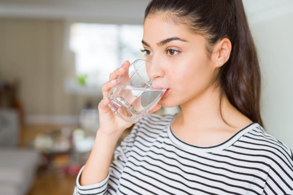 Beautiful Young Woman Drinking a Fresh Glass of Water at Home