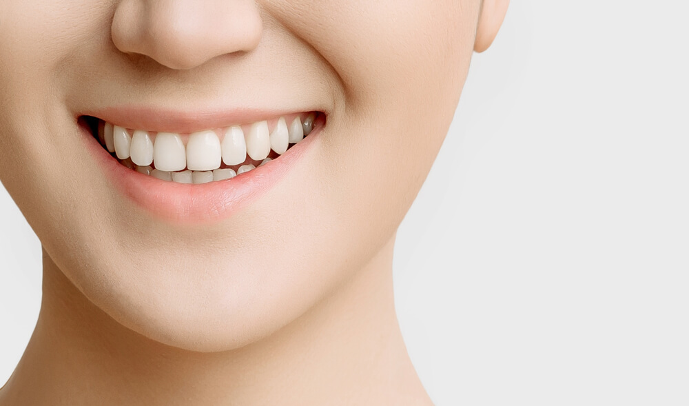 Smile of a Woman With Beautiful White Teeth Close-up on a White Background 