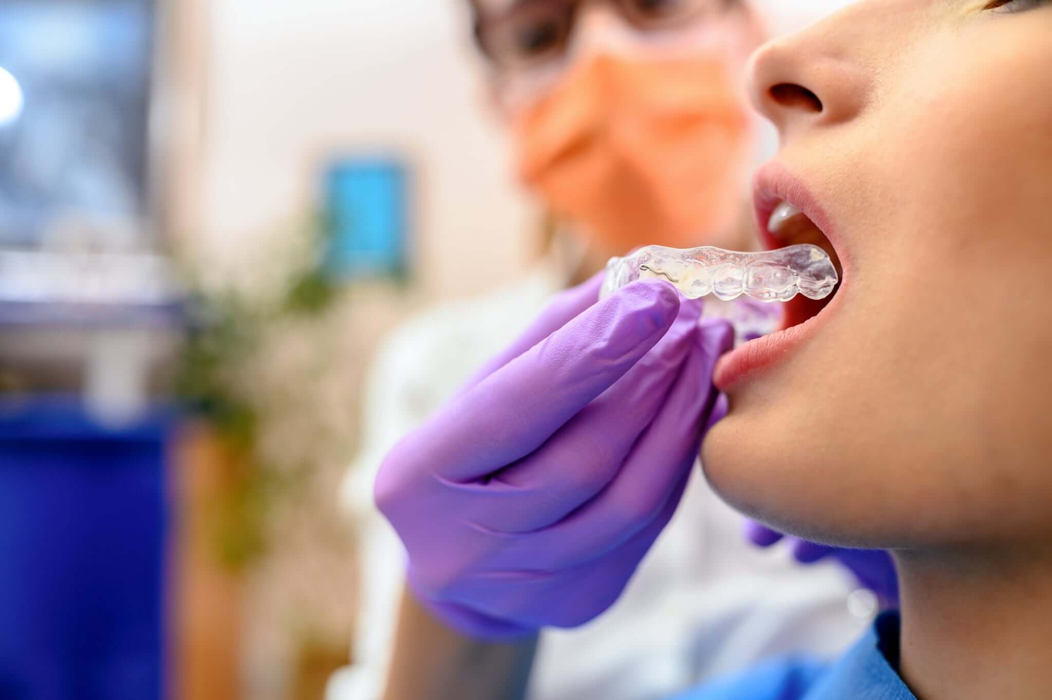 Dentist putting a mouthguard into her patients mouth