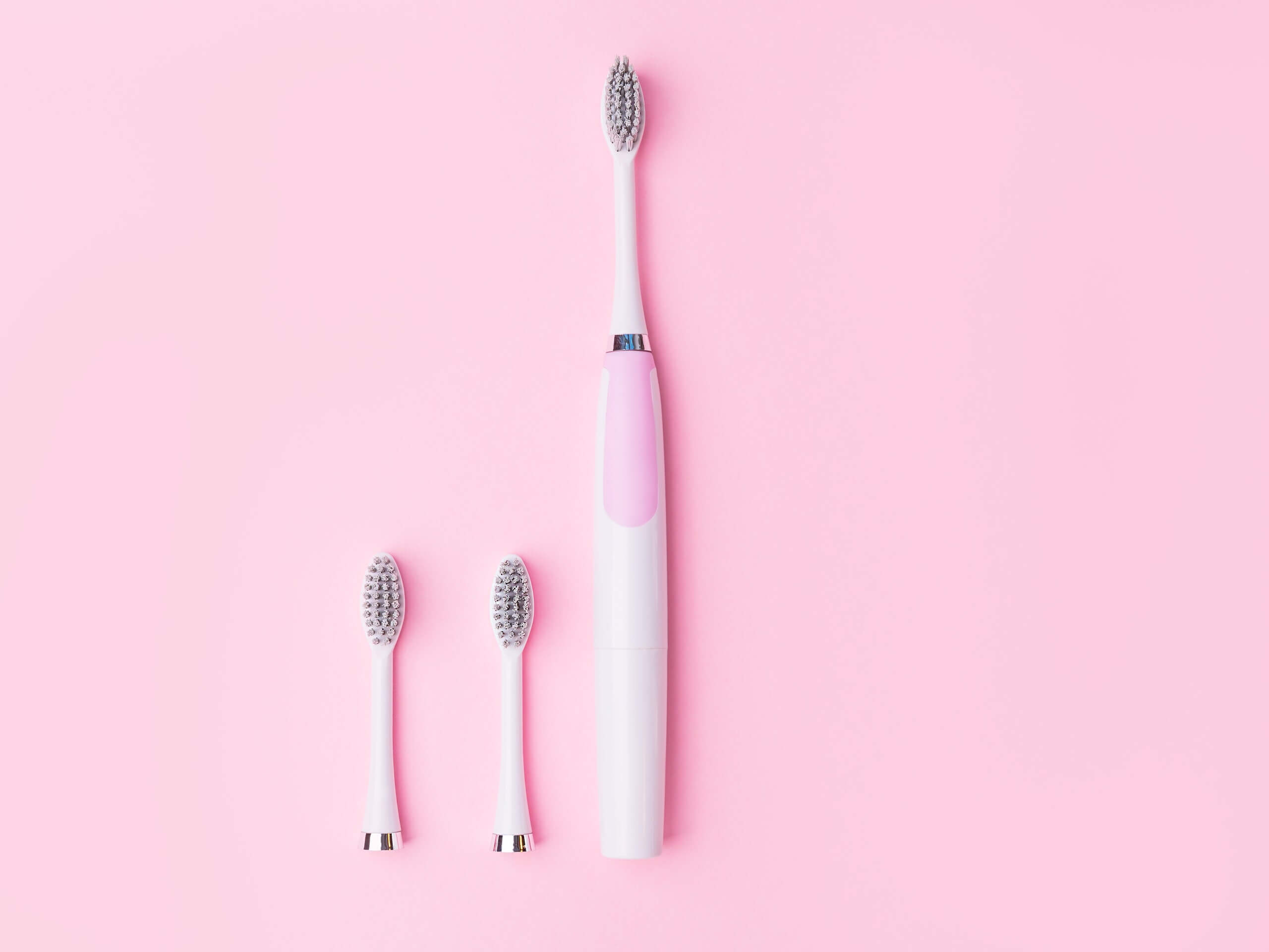 Pink and white toothbrush with two extra add-ons